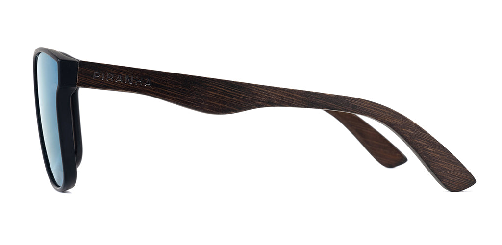 Left side facing view of a square black full rim sunglasses frame with blue mirror tinted lenses, lightweight plastic construction, dark brown bamboo temples, and a smooth finish on a white background. Featuring curved temples with san serif PIRANHA logo printed on the side.